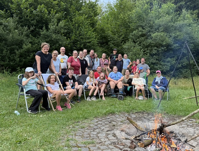 Glückliche und ganz unterschiedliche Menschen vor einem Lagerfeuer