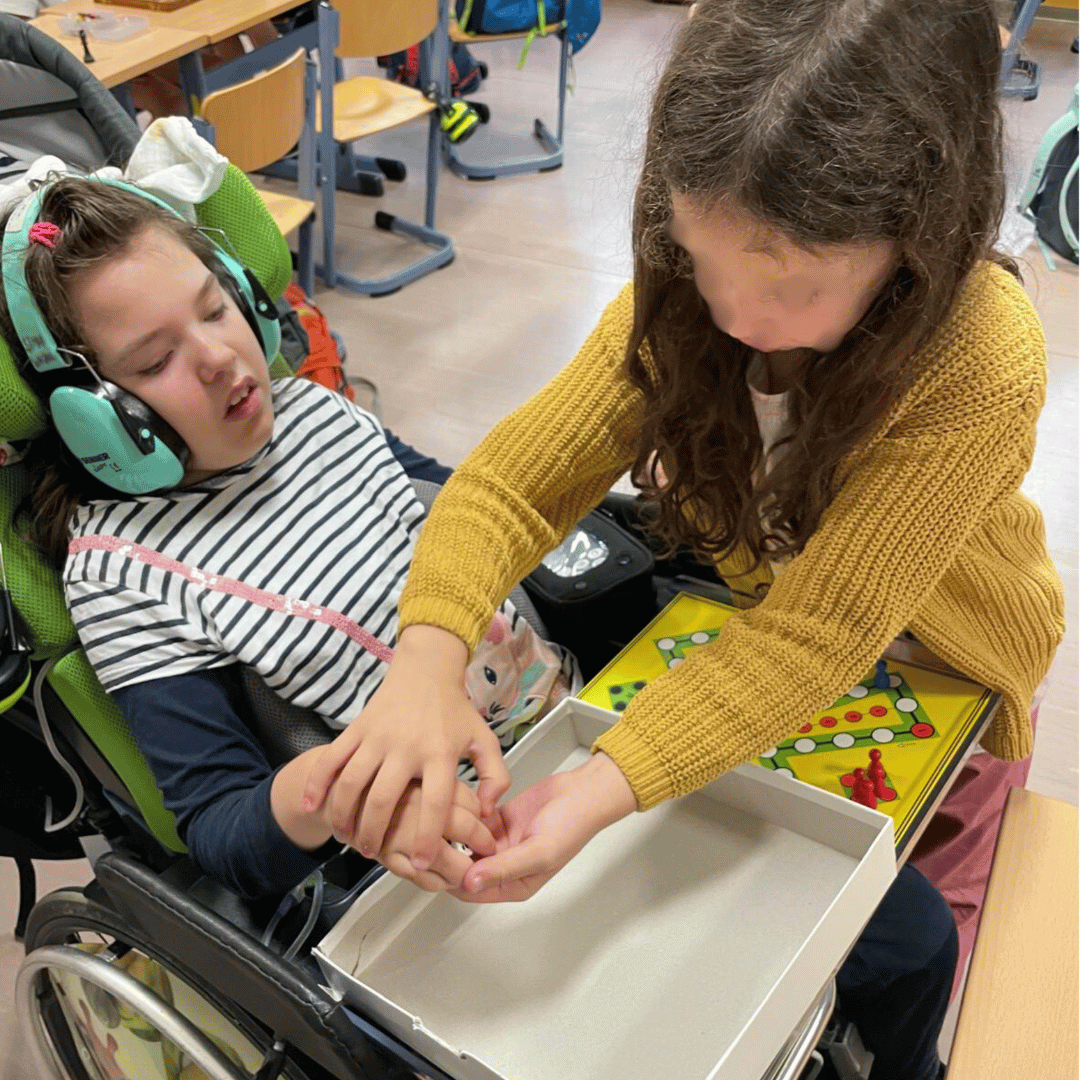 Ein Mädchen im Rollstuhl kann dabei sein, weil ein anderes Mädchen ihm hilft